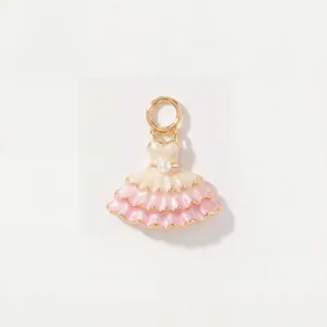 Gros plan détaillé d'un pendentif robe de ballet rose avec perle centrale et plaquage en or.