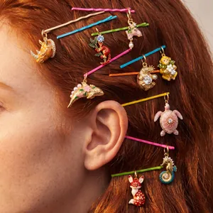 Gros plan de charms d'animaux en émail sur des épingles à cheveux dans les cheveux.