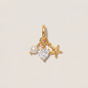 Close-up of golden pendant featuring pearl, heart-shaped crystal, and starfish charms.