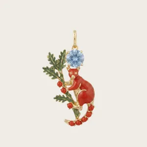 Gros plan détaillé du pendentif écureuil doré avec pierre bleu clair et baies en émail rouge