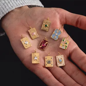Gros plan de pendentifs cartes de tarot plaqués or 18K avec zircons en main