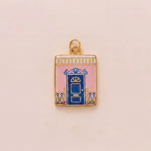 Detail view of a vintage rectangular enamel pendant featuring a pink villa and blue door.