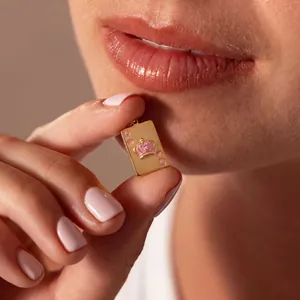 Détail d'un pendentif en acier titane doré en forme de carte de poker Reine rose.