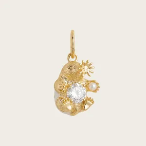 Gros plan d'un pendentif animal en or avec une pierre claire et une perle