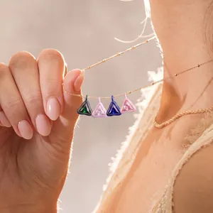 Detalle de cuatro colgantes triangulares de gemas de colores bañados en oro de 18 quilates.