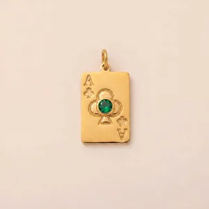 Détail d'un pendentif As de Trèfle en acier titane doré orné d'une pierre de zircon verte.