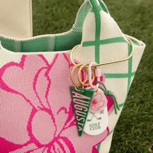 Close-up of fresh green and pink bag charms with Augusta and golf club motifs