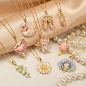Delicate enameled pink ballet dancer and floral charm necklaces on silk background.