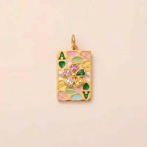 Vue détaillée d'un pendentif carte à jouer dorée avec motifs de macarons et fleur en gemmes