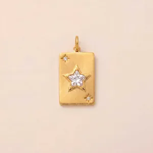 Détail d'un pendentif rectangulaire doré avec un zircon central en forme d'étoile.