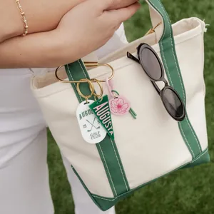 Close-up of Augusta golf club themed bag charms on a green and white canvas tote.