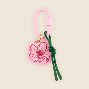 Close-up detail of a pink floral bag charm featuring a carabiner and green knotted rope