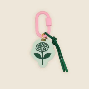 Close-up of a mint green hydrangea charm with pink carabiner and green knotted cord detail