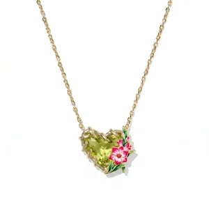 Nahaufnahme einer herzförmigen Halskette mit grünem Stein und rosa Emaille-Blumen
