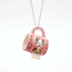 Detailed view of handmade miniature pink mug pendant necklace with cute rabbit and florals