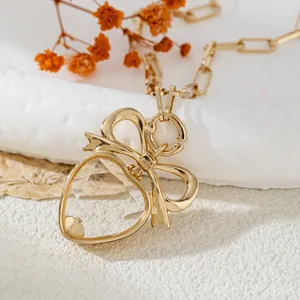 Gros plan d'un pendentif en verre transparent en forme de cœur avec un nœud doré