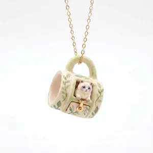 Detailed view of a miniature ceramic mug necklace with a cute white cat pendant.