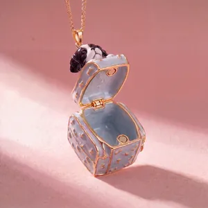 Close-up of openable enamel puppy box pendant with intricate gold bone patterns