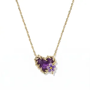 Detailansicht einer Goldkette mit lila Herz-Edelstein und kleiner violetter Blume.