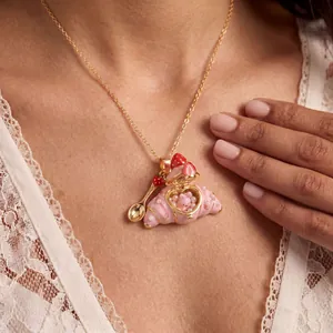 Detail einer aufklappbaren rosa Croissant-Halskette mit verstecktem Kaninchen und Löffel