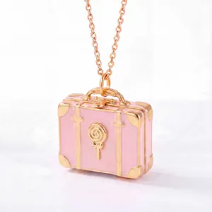 Detailansicht eines rosa Koffer-Halskettenanhängers mit goldenem Lutscher-Detail.