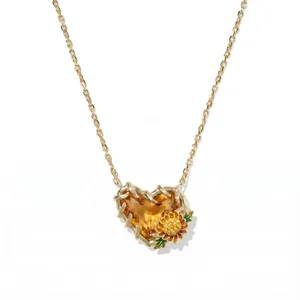 Detailaufnahme einer herzförmigen orangen Geburtsstein-Halskette mit goldener Blume