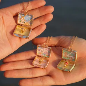 Detailansicht von drei Mini-Koffer-Halsketten mit magischen Märchenszenen im Inneren