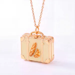 Detailansicht einer roségoldenen Mini-Koffer-Halskette mit Miniatur-Croissant- und Baguette-Design.
