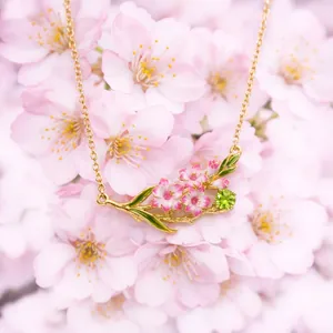 Close-up detail of vintage floral pendant necklace featuring pink petals and green gem