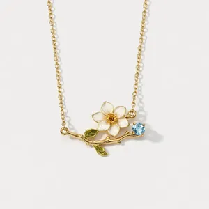 Detailed view of vintage floral necklace with white enamel flower and blue gemstone.