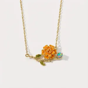 Detail view of a vintage gold-tone necklace with an orange enamel flower pendant.