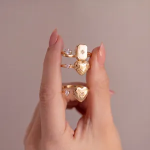 Primer plano detallado de anillos de relicario para fotos dorados en forma de corazón y rectángulo