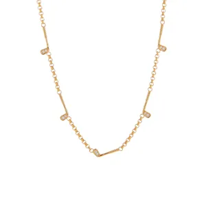 Détail d'un collier en chaîne dorée avec cinq mini pendentifs de club de golf et pierres.
