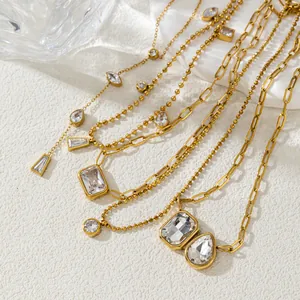 Close-up of layered gold paperclip and ball chain necklaces with sparkling clear crystals