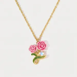 Close-up detail of gold-tone necklace with pink enamel roses and a moonstone accent