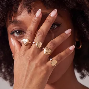 Detalle de anillos de relicario dorados con diseños de corazón y óvalo con estrella