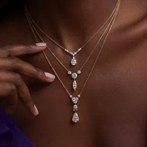 Detailaufnahme von drei geschichteten Goldketten mit exquisiten Diamantanhängern