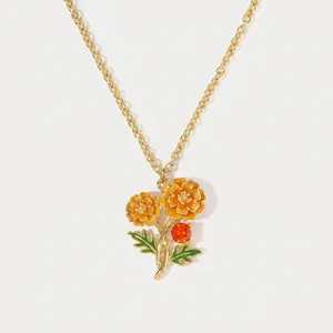 Close-up detail of a handmade orange enamel birth flower necklace with a gold chain.