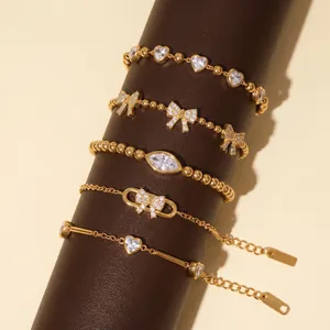 Detailansicht goldener Titanstahlarmbänder mit Herz- und Schleifenmotiven