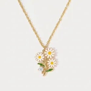 Detailed macro shot of a dainty gold daisy necklace with white enamel flowers and a crystal.