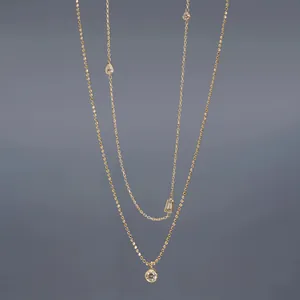 Detailed view of layered gold chains with pear and emerald cut crystal pendants.