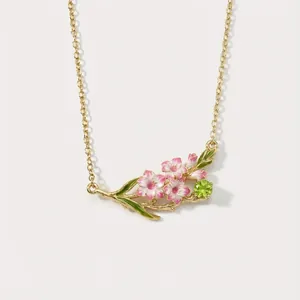 Vintage style gold-tone necklace featuring pink enameled flowers and a green gemstone