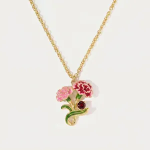 Detailed view of enamel carnation flower pendant necklace with red gem on gold chain