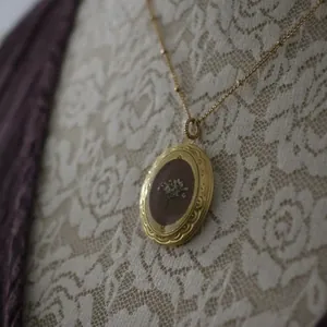 Detailansicht einer Vintage-Medaillon-Halskette aus 14 Karat Gold mit Trockenblumen