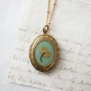 Detail einer Vintage-Medaillon-Halskette mit getrockneter Blume auf Pergament