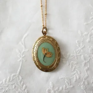 Vintage 14k Goldmedaillon-Halskette mit echter Trockenblume auf weißem Spitzenhintergrund