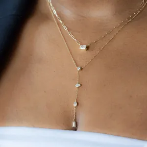 Detail of layered gold necklaces with emerald-cut and multi-shaped crystal pendants.