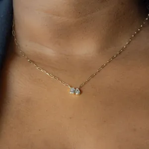Close-up of gold paperclip chain necklace with baguette and pear-shaped diamond pendants