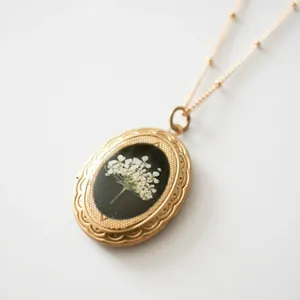 Nahaufnahme einer Vintage 14k Gold Medaillonkette mit echten weißen Trockenblumen