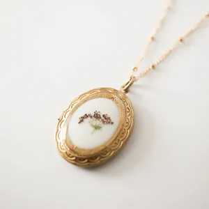 Detailansicht eines vintage ovalen Goldmedaillon-Halskette mit echten Trockenblumen